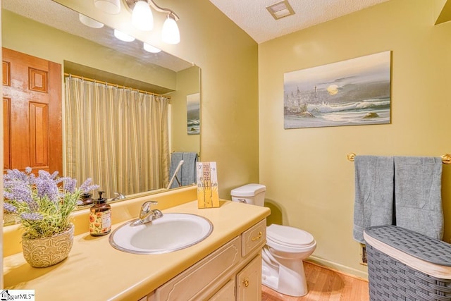 full bath featuring visible vents, toilet, a textured ceiling, wood finished floors, and vanity