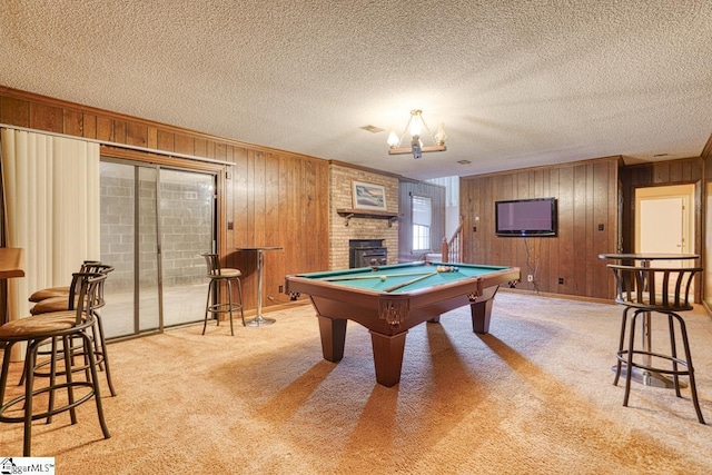 recreation room featuring a textured ceiling, pool table, wood walls, and carpet flooring