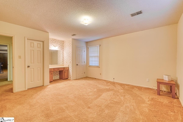 unfurnished bedroom featuring visible vents, baseboards, light colored carpet, and a textured ceiling