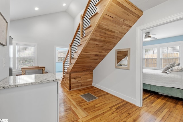 stairs featuring visible vents, baseboards, recessed lighting, hardwood / wood-style flooring, and high vaulted ceiling