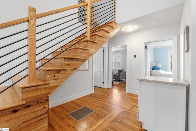 stairs with wood finished floors, visible vents, and baseboards