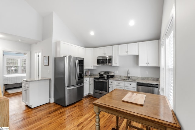 kitchen with a sink, stainless steel appliances, light wood-style flooring, and white cabinetry