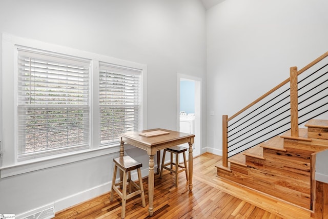 stairway featuring visible vents, a high ceiling, baseboards, and hardwood / wood-style flooring