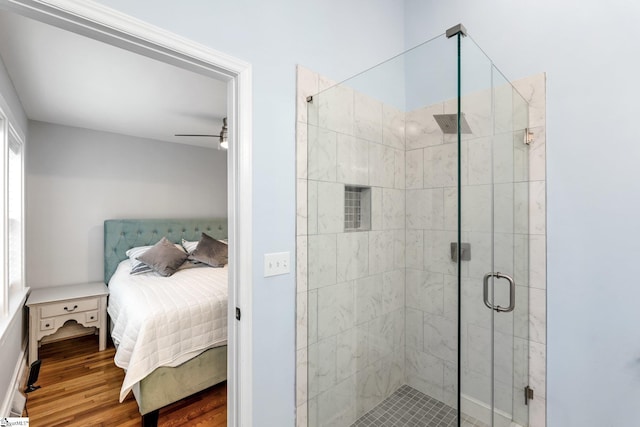 ensuite bathroom with a ceiling fan, wood finished floors, a stall shower, and connected bathroom