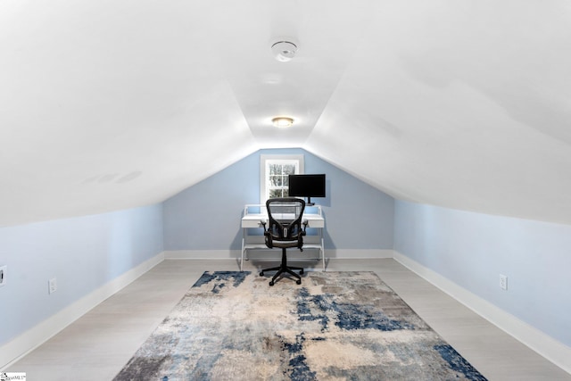 home office with baseboards, lofted ceiling, and light wood-style floors