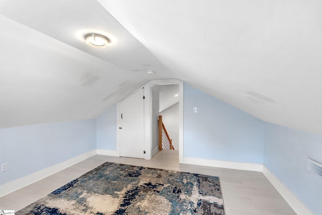 additional living space with visible vents, baseboards, lofted ceiling, and light wood-style flooring