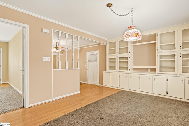 unfurnished dining area featuring crown molding, light wood-style floors, and baseboards