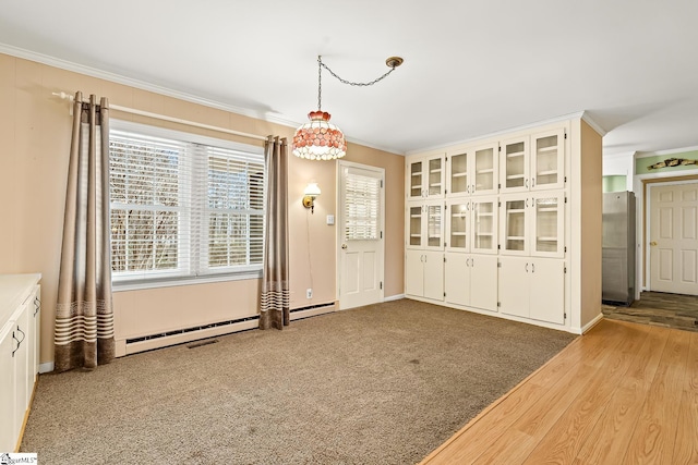 unfurnished dining area featuring carpet, baseboard heating, and crown molding