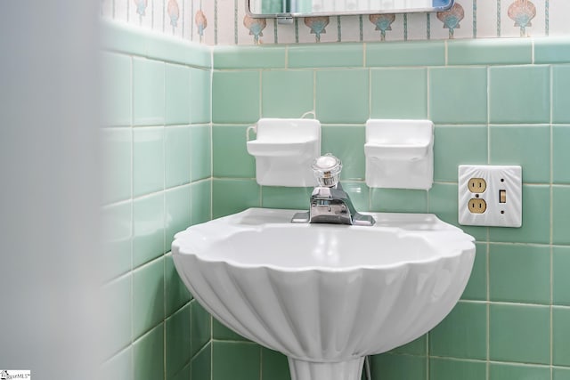 bathroom featuring a wainscoted wall, wallpapered walls, tile walls, and a sink