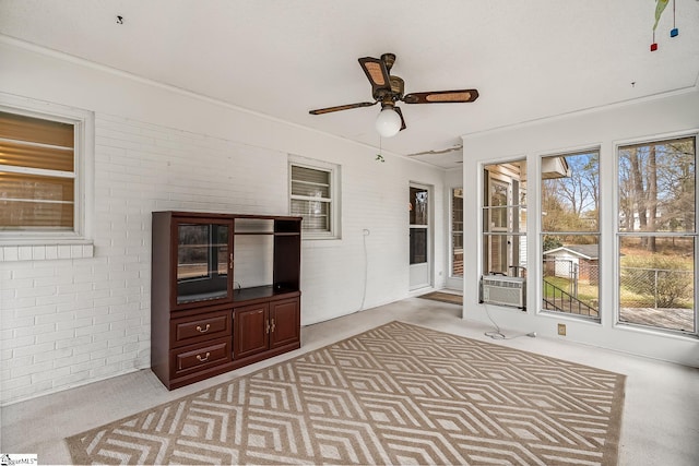 unfurnished sunroom featuring cooling unit, a healthy amount of sunlight, and ceiling fan