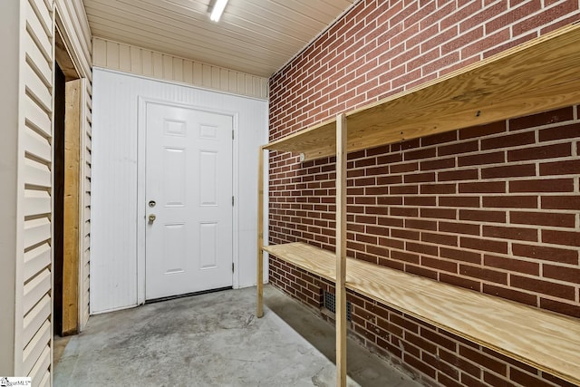 exterior space featuring unfinished concrete flooring and brick wall