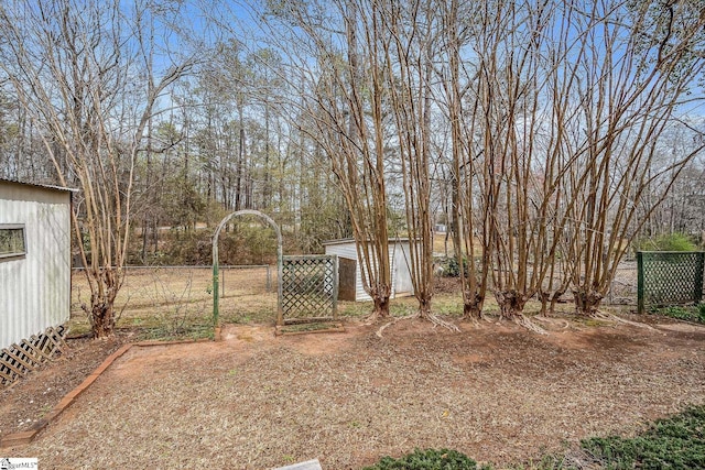 view of yard with a storage shed, an outdoor structure, and fence