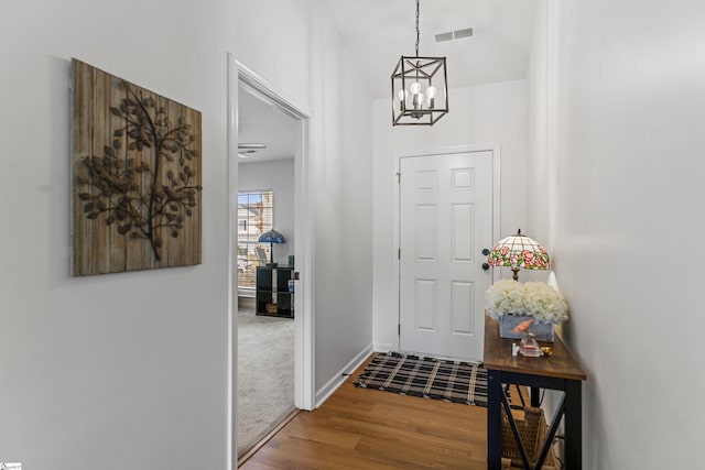 entrance foyer featuring a notable chandelier, wood finished floors, visible vents, and baseboards