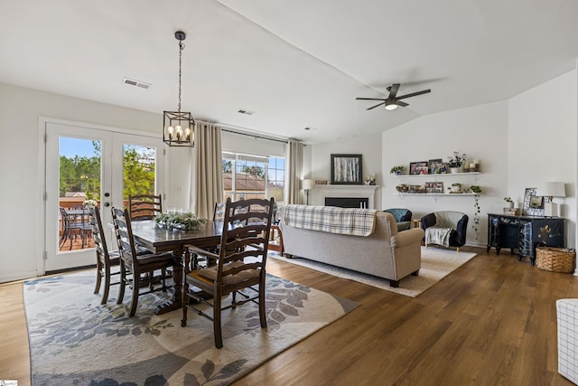 dining room with visible vents, lofted ceiling, wood finished floors, and ceiling fan with notable chandelier