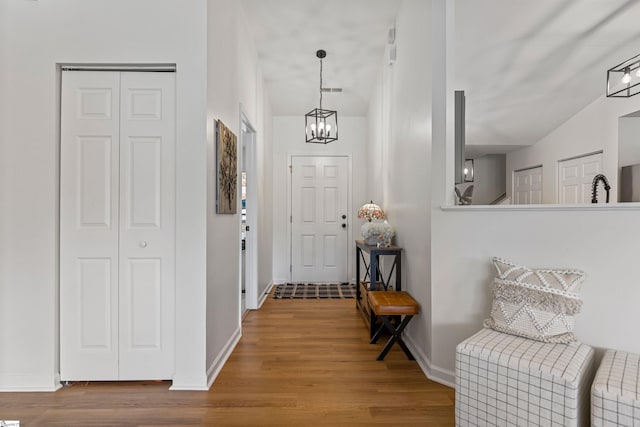 entryway featuring a chandelier, baseboards, and wood finished floors