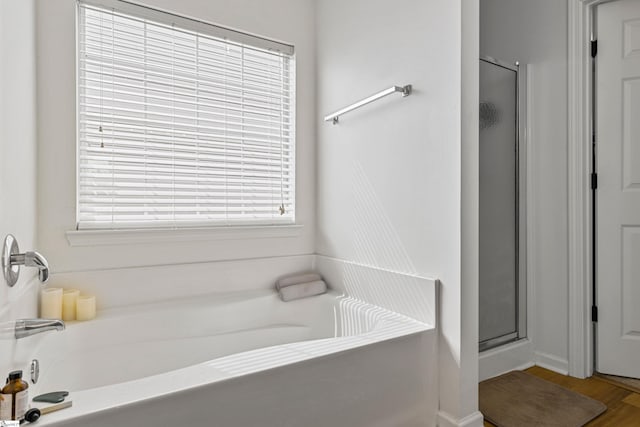 bathroom with a stall shower and a garden tub