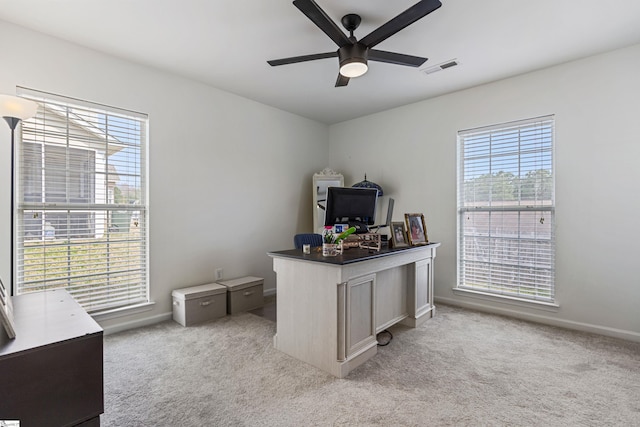 office featuring visible vents, light colored carpet, baseboards, and a ceiling fan