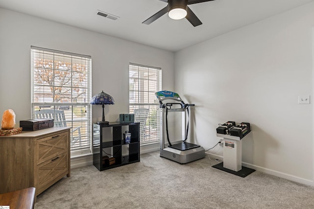 exercise area featuring visible vents, light carpet, baseboards, and a ceiling fan