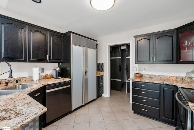 kitchen with dishwasher, built in refrigerator, stainless steel range with electric stovetop, dark cabinetry, and a sink