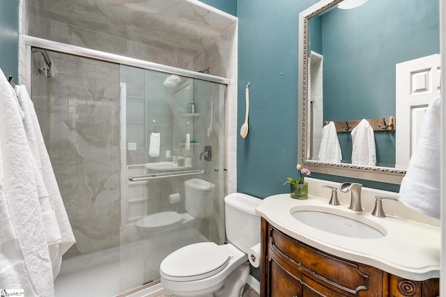 full bathroom with vanity, a shower stall, and toilet