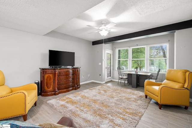 living area with a textured ceiling, a ceiling fan, and wood finished floors