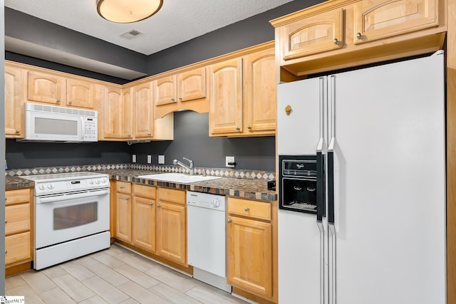 kitchen with a sink, white appliances, a textured ceiling, and light brown cabinetry