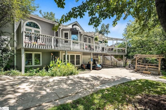 back of property featuring stucco siding, a wooden deck, and a pergola