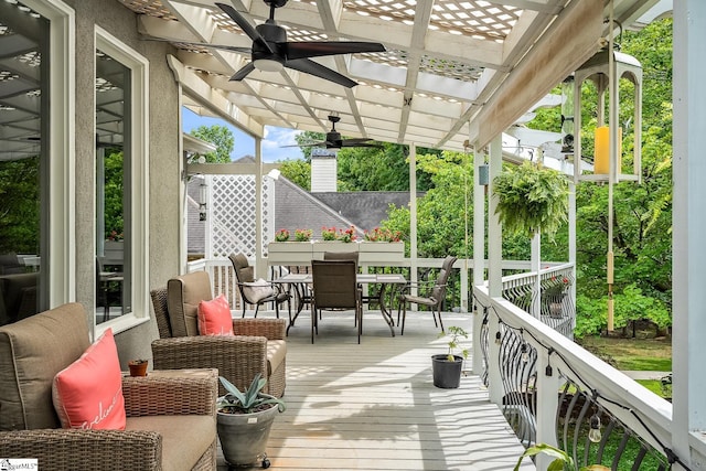 deck featuring outdoor dining area, ceiling fan, and a pergola