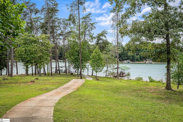 view of community featuring a yard, a water view, and a boat dock