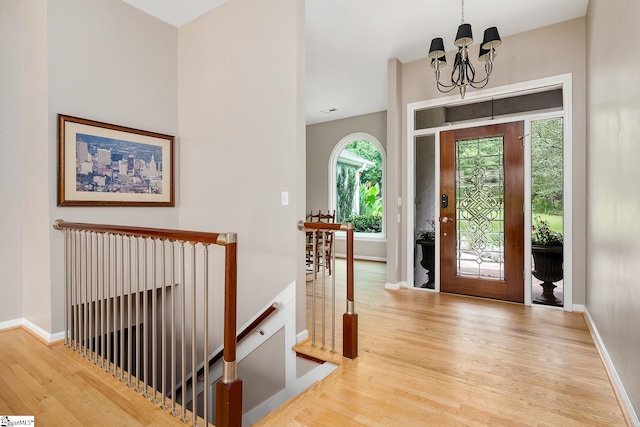 foyer entrance featuring an inviting chandelier, wood finished floors, and baseboards