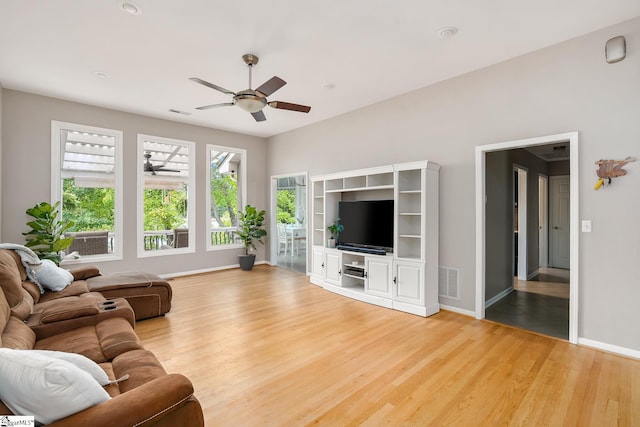 living area with visible vents, baseboards, light wood-style floors, and ceiling fan