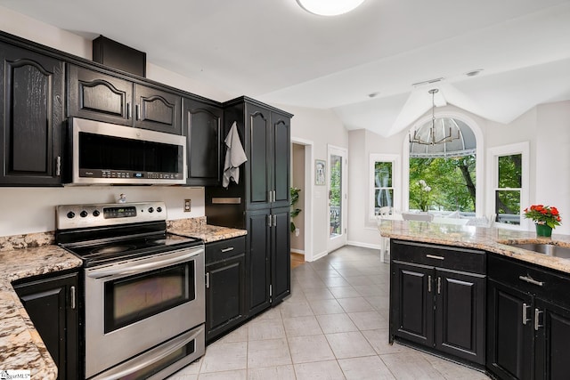 kitchen with appliances with stainless steel finishes, dark cabinetry, and vaulted ceiling