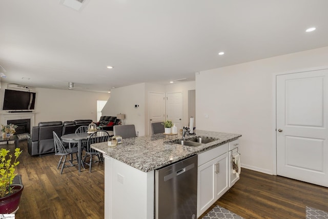 kitchen with a sink, light stone counters, stainless steel dishwasher, dark wood finished floors, and white cabinetry