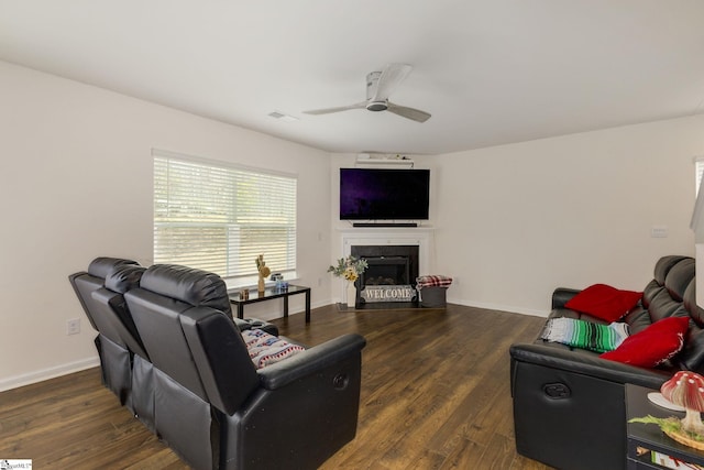 living area with wood finished floors, baseboards, visible vents, a fireplace, and ceiling fan