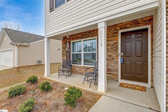 doorway to property with stone siding, a porch, and an attached garage