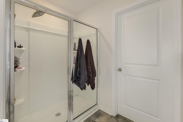 bathroom with a shower stall and stone finish floor