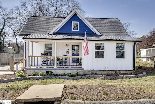 bungalow-style home featuring covered porch, metal roof, and fence