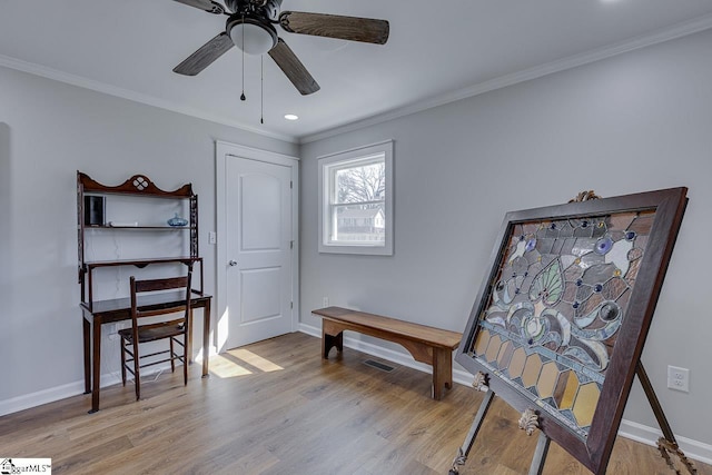 living area featuring baseboards, crown molding, and light wood finished floors