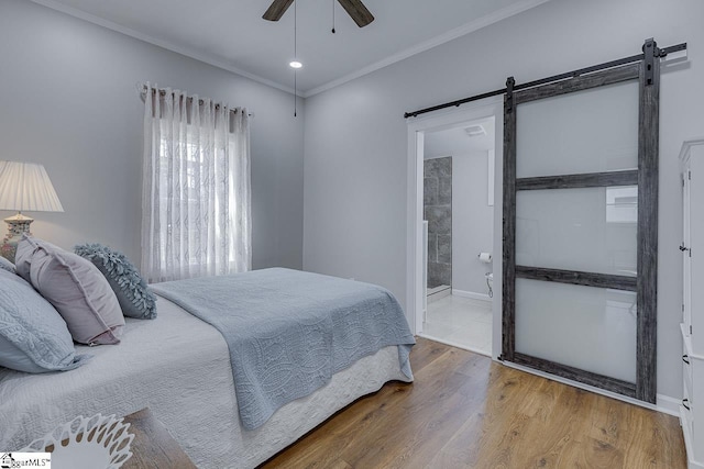 bedroom with a ceiling fan, a barn door, crown molding, and wood finished floors