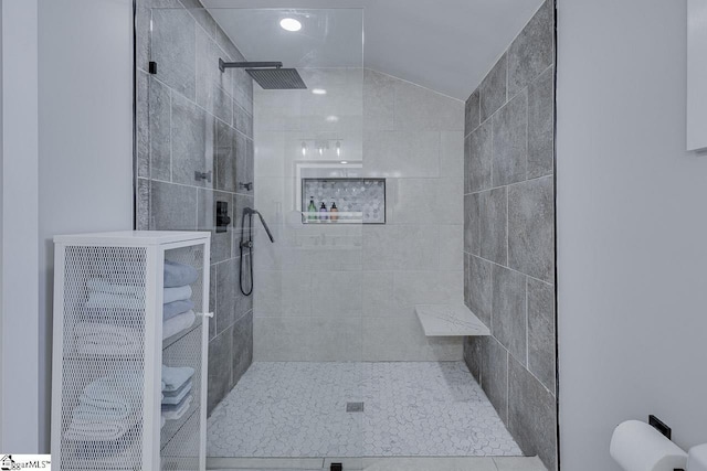 bathroom with heating unit, tiled shower, and vaulted ceiling