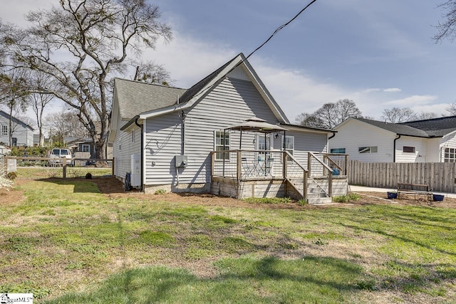 back of house with a lawn, a deck, and fence