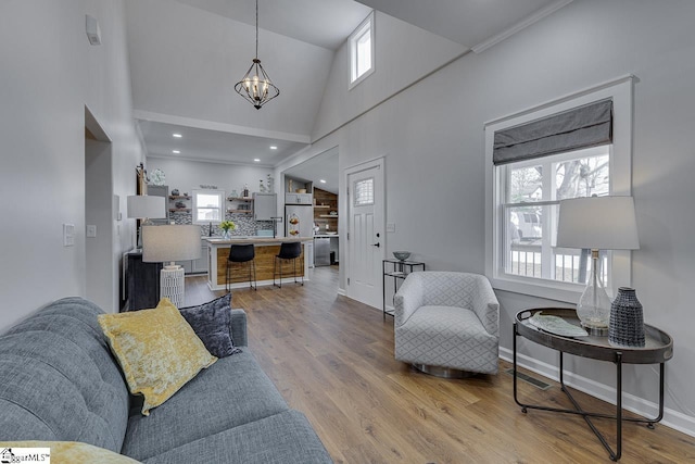 living room featuring wood finished floors, baseboards, recessed lighting, a towering ceiling, and a chandelier