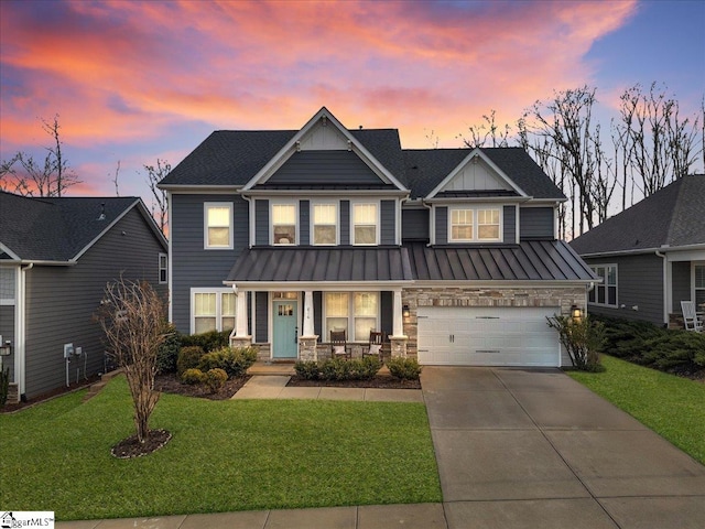 craftsman-style house featuring driveway, a standing seam roof, stone siding, a yard, and covered porch