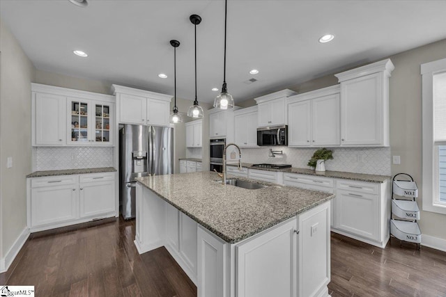 kitchen featuring a center island with sink, a sink, dark wood-style floors, white cabinetry, and stainless steel appliances