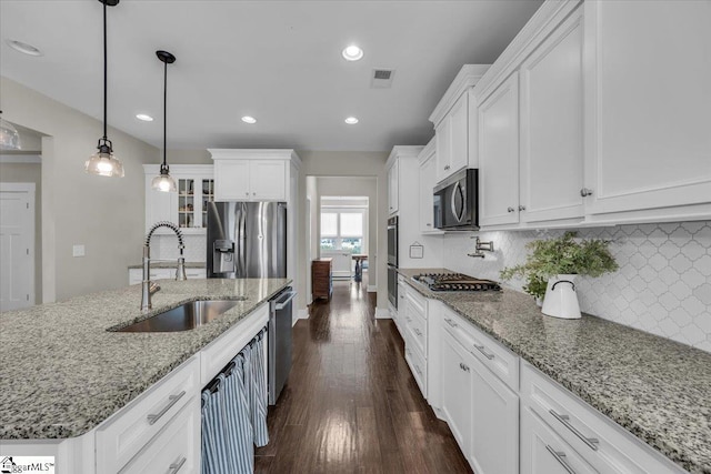 kitchen featuring backsplash, dark wood-style floors, white cabinets, stainless steel appliances, and a sink