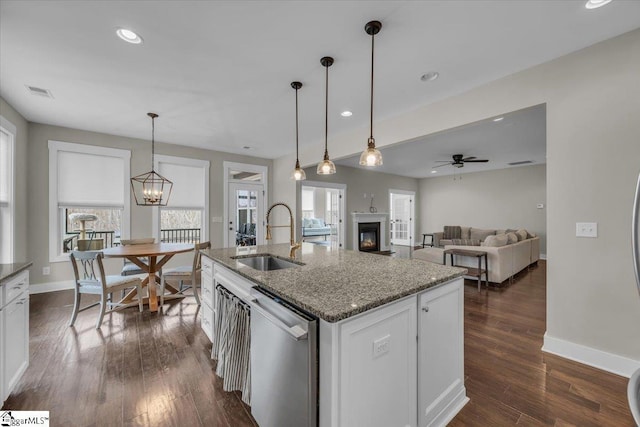 kitchen featuring visible vents, a sink, a glass covered fireplace, white cabinetry, and dishwasher