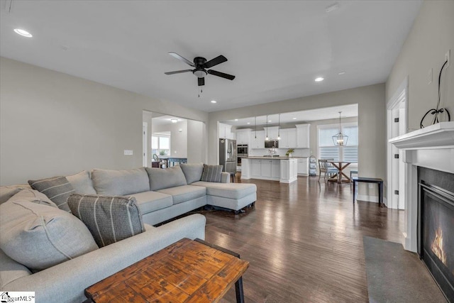 living room with baseboards, recessed lighting, ceiling fan, dark wood-type flooring, and a glass covered fireplace