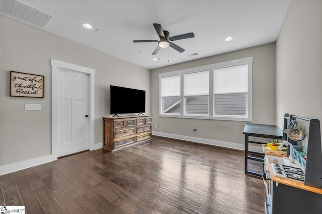 living area with baseboards, wood finished floors, visible vents, and ceiling fan