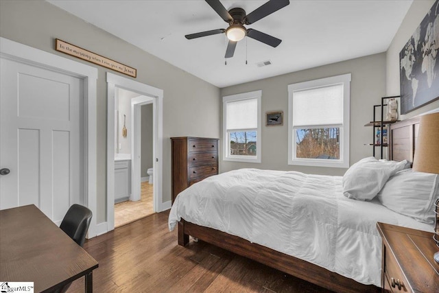 bedroom with visible vents, ensuite bath, baseboards, ceiling fan, and dark wood-style flooring