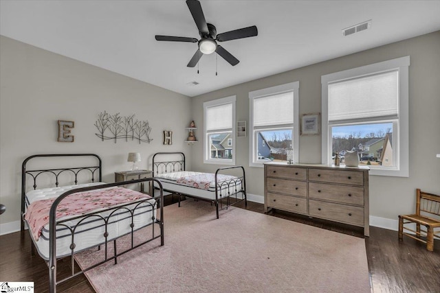 bedroom with visible vents, baseboards, dark wood-style floors, and a ceiling fan